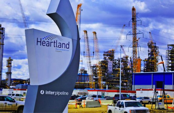 Heartland Petrochemical complex front gate with sign and facility under construction in background